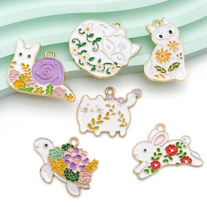 Close-up of colorful floral enamel animal charms with gold alloy frames for DIY jewelry