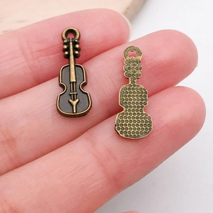 Macro shot of violin alloy pendants in antique bronze finish on a fingertip