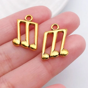 Makroaufnahme von zwei goldenen Sechzehntelnoten-Anhängern mit Ringen für DIY-Schmuck