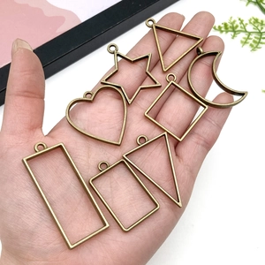 Assorted bronze alloy geometric pendant frames for DIY jewelry crafts held in palm