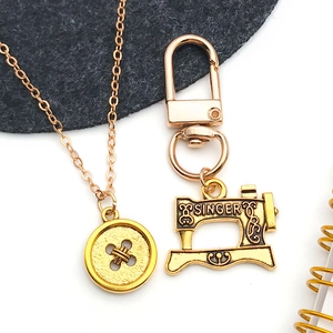 Macro-opname van gouden naaimachine en knoopbedels voor DIY-sieraden en sleutelhangers