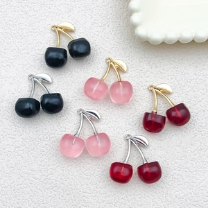 Close-up of resin cherry pendants in red, pink, and black with metallic leaf details