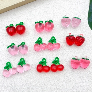 Flat lay of colorful acrylic DIY fruit charms including strawberries and cherries