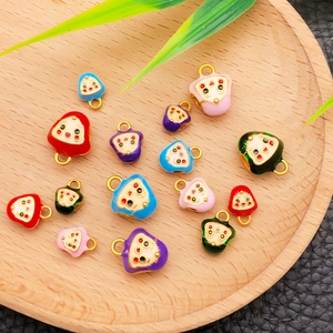Gros plan de pendentifs Daruma en émail coloré avec boucles en métal sur un plateau