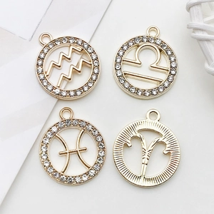 Détail de quatre pendentifs zodiaque dorés sertis de diamants et gravures sur fond blanc