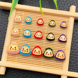 Macro detail of colorful enamel rice dumpling charms on a bamboo tray for DIY jewelry