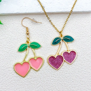 Detail of heart-shaped cherry charms with pink enamel and purple glitter for jewelry DIY