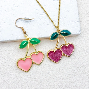 Pink heart cherry jewelry set with necklace and earrings on white textured background