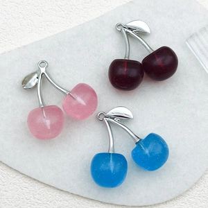Macro detail of cherry pendants in red, pink, and blue with frosted resin and silver stems