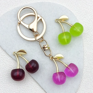 Close-up of translucent purple resin cherry charms with gold alloy lobster clasps