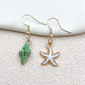 Détail de boucles d'oreilles S925 asymétriques avec pendentifs de conque verte et étoile de mer
