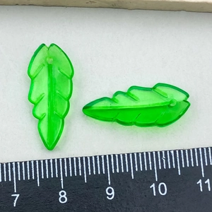 Macro view of transparent green acrylic leaf charms with a ruler showing 25mm length