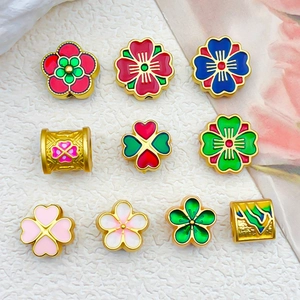 Vue macro de perles fleurs en émail coloré et breloques Fu pour la création de bijoux DIY
