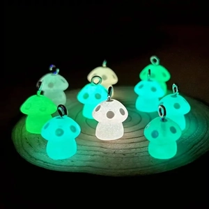 Colgantes de setas de resina luminosa con aros metálicos brillando sobre madera