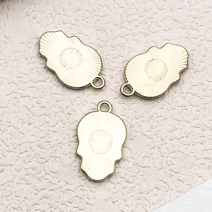 Detailansicht von drei goldenen Anhängern mit Sonnenstrahl-Muster für DIY-Schmuck