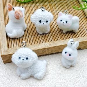 Close-up of white flocked Corgi and Bichon Frise animal charms with metal loops