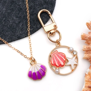 Macro shot of gold-plated shell pendant and starfish charm with purple enamel inlay