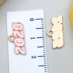 Detalle macro de un colgante 2025 de esmalte rosa y oro de 2 cm con reverso texturizado