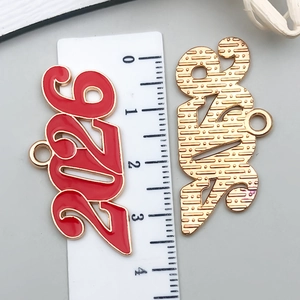 Detalle macro del colgante 2026 de aleación con esmalte rojo y reverso dorado texturizado