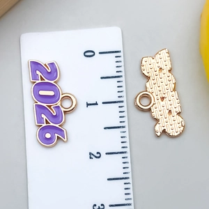 Detalle del colgante de esmalte morado 2026 con regla para referencia de tamaño