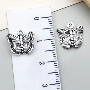 Detail of vintage silver butterfly pendant with size measurement shown on a ruler