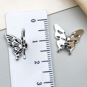 Macro detail of vintage hollow silver butterfly charm with ruler scale for size measurement