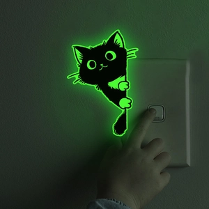 Sticker mural chat noir mignon et lumineux brillant en vert près d'un interrupteur mural