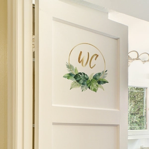 Modern WC door decal featuring golden lettering and tropical green leaves on white wood
