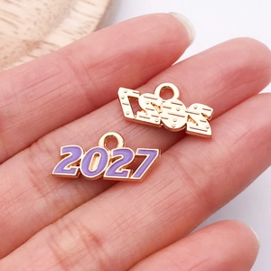 Macro de pendentifs dorés 2024 et 2027 avec émail violet et finitions métalliques texturées