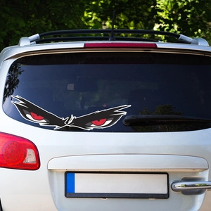 Car decal featuring fierce red monster eyes on the rear window of a silver vehicle