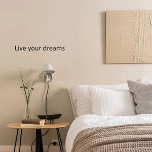 Detail showing 'Live your dreams' black quote wall sticker in a minimalist bedroom setting