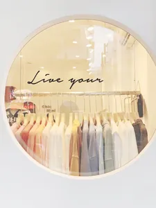 Detailed view of colorful cotton T-shirts hanging on wooden hangers in a boutique window