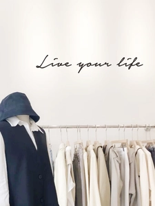 Detail view of cotton sun hat and minimalist layered outfit on a shop display rack
