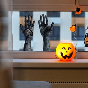 Halloween scary zombie hand stickers on window glass with glowing pumpkin decor