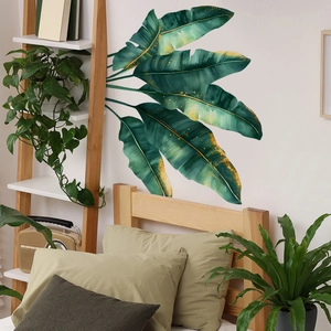 Tropical monstera wall decal with golden splashes on bedroom wall above bed