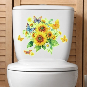 Dettaglio degli adesivi con girasoli e farfalle applicati su un sedile WC bianco