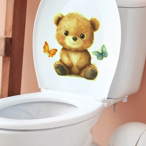 Glow-in-the-dark cute brown bear and butterfly stickers on a white toilet lid in a cozy bathroom