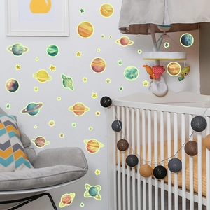 Luminous planet and stars wall decals glowing in a cozy nursery room setting
