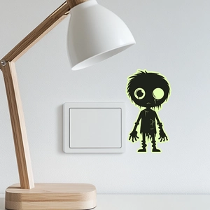 Glow-in-the-dark Halloween alien boy sticker applied near a light switch on a white wall