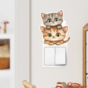 Detail of stacked cartoon cat light switch stickers on a white wall surface