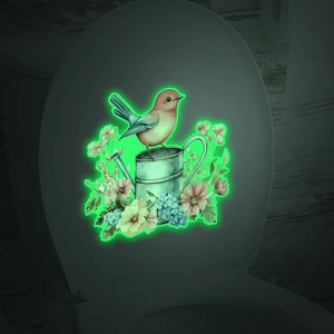 Glow in the dark bird and floral sticker showing luminous green effect on a toilet lid