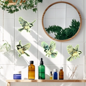 Detailed view of four glowing sparrow wall stickers on a white tile bathroom wall