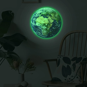 Luminous Earth wall decal glowing green in a cozy bedroom with a plant and wooden chair
