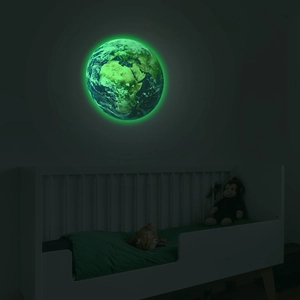 Luminous earth wall sticker glowing green in a dark children's room over a crib
