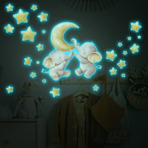 Luminous wall stickers showing a moon, elephants, and stars glowing bright blue in the dark