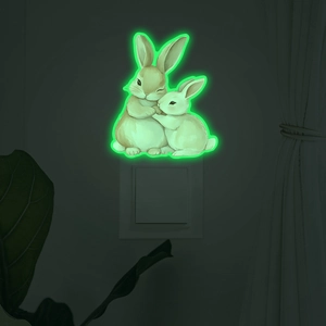 Luminous wall sticker featuring cute hugging rabbits glowing green on light switch