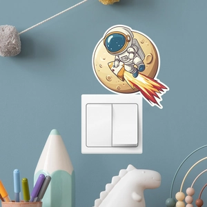 Detail of cartoon astronaut and rocket wall sticker on a blue wall above a white switch