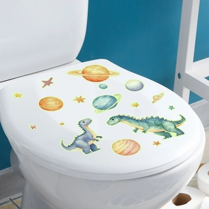 Glow-in-the-dark dinosaur and space toilet stickers shown on a white lid in a bathroom