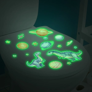 Luminous dinosaur and planet stickers glowing in the dark on a white toilet lid