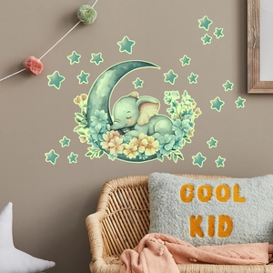 Glow-in-the-dark wall sticker of a sleeping elephant on a moon with stars in a nursery